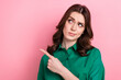 © deagreez - Photo of sweet uncertain lady wear green shirt looking pointing finger empty space isolated pink color background