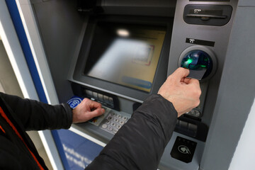 A bank customer using debit, and credit card to complete a transaction via ATM automated teller machine