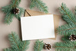 Blank Christmas holiday greeting card mockup with envelope and fir tree branches with cones, copy space