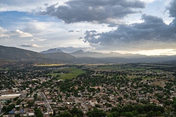 Poster - a town with mountains and buildings in the background under a cloudy sky