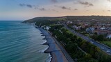 Fototapeta Na sufit - Aerial view of houses near a road along the sea in England at sunset