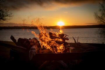 Wall Mural - Stunning beachside scene with a bonfire blazing in the foreground at sunset