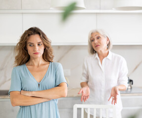 Aggrieved elderly woman having quarrel with her daughter at home. Elderly mother expresses claims to adult daughter