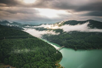 Sticker - Aerial view of a tranquil lake surrounded by mountains and a beautiful sky filled with white clouds