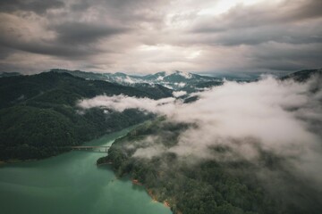 Canvas Print - clouds hover over the mountains in front of a green lake