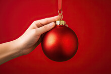 A Hand Holding A Red Ornament On A Red Background Created With Generative AI Technology