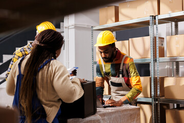 Post office warehouse managers checking parcel invoice before delivery. African american woman putting black case on table for packing before transportation in retail storehouse