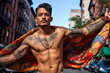 © ADDICTIVE STOCK - Generative AI illustration from below of Young tattooed chicano with a bare torso holding a flag looking at the camera in town blurred background