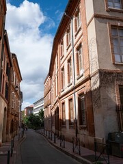 Canvas Print - Narrow street lined with red brick buildings in Toulouse