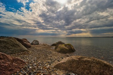 Wall Mural - sun breaks through clouds as it shines down on rocks in the middle