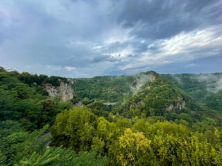 Poster - Scenic view out of lush greenery against the background of a cloudy sky. Pitigliano, Italy.