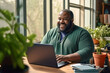 © MVProductions - Portrait of an overweight African American man working from home on a laptop computer