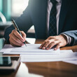 Close-up of a person's hand signing a contract with a pen on a desk, businessman writing on paper report in office.Laywer hands signing divorce papers. Signatures on legal document