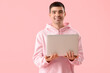 © Pixel-Shot - Young man with laptop on pink background