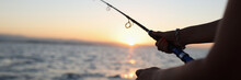 Woman Holding Fishing Rod In Her Hands, Sunset Above Sea In Background.