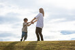 © 健二 中村 - 丘の上で手を繋ぐ親子　Parent and child holding hands