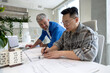 © zinkevych - Men working with 3D printer and blueprint for designing mechanical parts in high tech workshop.