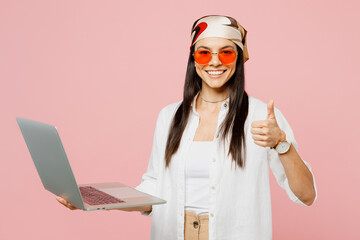 Poster - Side view young IT latin woman she wear white shirt casual clothes sunglasses hold use work on laptop pc computer shwo thumb up isolated on plain pastel light pink background studio Lifestyle concept