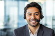 © Liubomir - Close-up portrait of young successful businessman with headset phone, customer support worker in business suit smiling and looking at camera, workplace inside office.