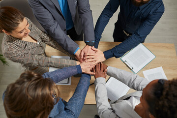 Wall Mural - Business people group putting their hands on top of each other. View from above of cheerful multiethnic colleagues making a stack of hands.Teamwork, collaboration, unity concept