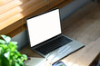 © Prathankarnpap - Laptop, notepad, smartphone and houseplant on wooden table near window. Empty screen for your advertising text message