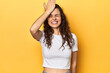 Young Caucasian woman, yellow studio background, forgetting something, slapping forehead with palm and closing eyes.