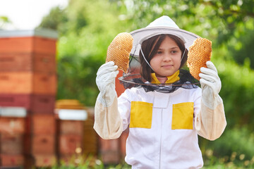 Wall Mural - Girl examining organic beeswax at apiary garden