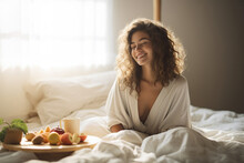 Happy Young woman eating breakfast in bed