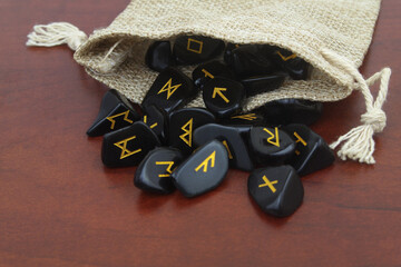 Wall Mural - Black stone runes with burlap sack on wooden table.