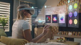 Fototapeta  - Woman in VR headset chooses clothes in online store chilling at home. 3D futuristic hologram shows widgets in user menu and clothing store website interface. VFX animation. Concept of online shopping.