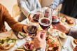 © Seventyfour - Close up of people toasting with red wine glasses at festive dinner table, copy space