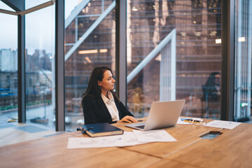 Wall Mural - Businesswoman sitting at table with laptop in office