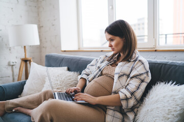 Pregnant woman working from home on netbook