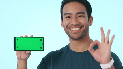 Poster - Happy asian man, face and phone green screen, mockup or pointing in advertising against a studio background. Portrait of male person smile or ok on mobile smartphone app, tracking marker or display