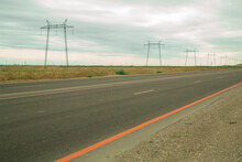 Electric Transmission Lines Along The Highway In The Steppe Against The Background Of The Evening Cloudy Sky