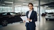 Portrait of beautiful saleswoman holding tablet and smiling at car showroom
