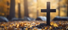 Autumn Cemetery With A Black Cross On A Headstone Made Of Granite