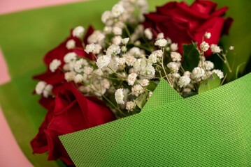 Canvas Print - Closeup of a bouquet of beautiful red roses on a pink surface