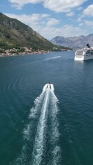 Canvas Print - Drone vertical view over a motorboat driving and Coastal of Kotor town in a distance in Montenegro