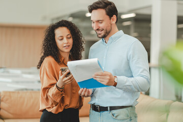 Bearded middle aged ceo businessman holding documents, female secretary holding mobile phone