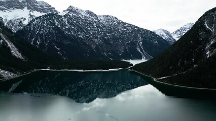 Wall Mural - Aerial video of the lake reflecting rocky mountains covered with snow