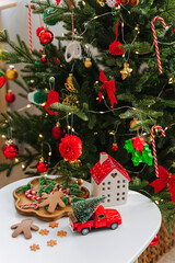 Wall Mural - Christmas holidays. Little houses, toys and christmas decorations on the table next to the Christmas tree. Holiday Activity for Kids. Merry Christmas and Happy Holidays!