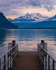 Canvas Print - a dock with snow capped mountains in the background and a calm lake