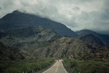 Canvas Print - Car driving on a highway mountain road surrounded by lush green vegetation