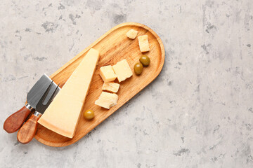 Wall Mural - Wooden board with pieces of tasty Parmesan cheese on grunge background