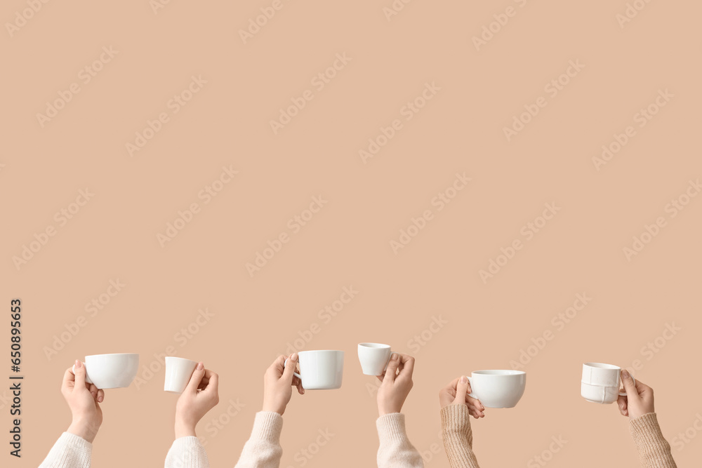 Female hands holding cups on beige background