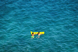 Fototapeta  - Młoda dziewczyna w stringach płynie na materacu po morzu.
