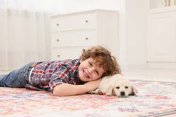 Sticker - Little boy lying with cute puppy on carpet at home