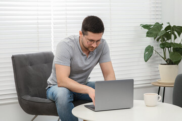 Wall Mural - Man working with laptop at table in living room