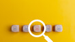 © FAMILY STOCK - Searching for a new job concept. Magnifying glass and wooden cube with people icons. Online recruitment application specialist search service concept